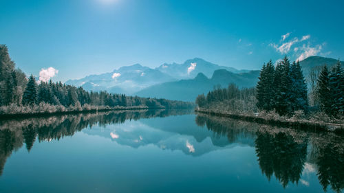 Scenic view of lake and mountains against blue sky