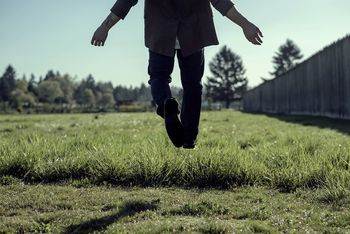 Low section on man levitating over grassy field