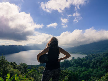 Rear view of woman looking at lake against sky