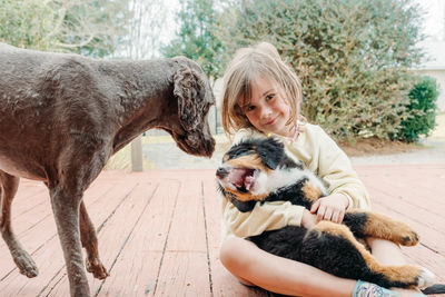 Concept of love to animals and friendship with pets adorable cute child girl with puppy dog on porch
