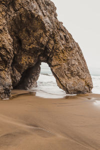 Rock formation on beach against sky