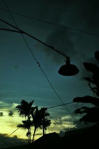 Low angle view of power lines against cloudy sky