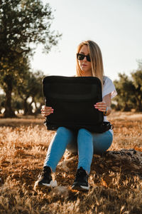 Woman using laptop while sitting at olive orchard