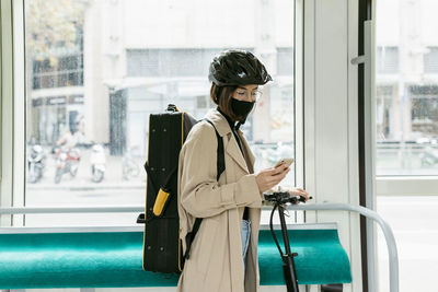 Woman standing by glass window in city