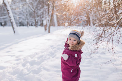 Portrait of girl standing on snow covered field