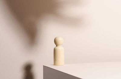 Wooden figurine on a beige background. loneliness