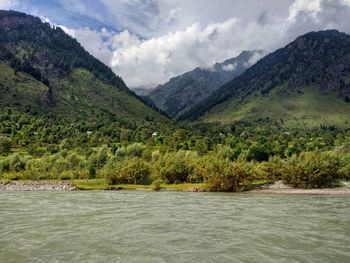 Scenic view of river and mountains against sky