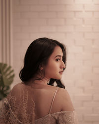 Portrait of a beautiful young woman standing against wall