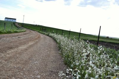 View of field against cloudy sky