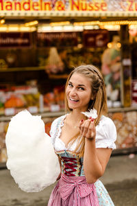 Portrait of happy woman eating cotton candy at oktoberfest