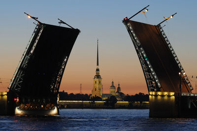 Cranes at commercial dock against sky during sunset