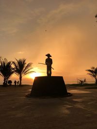 Silhouette statue at beach during sunset