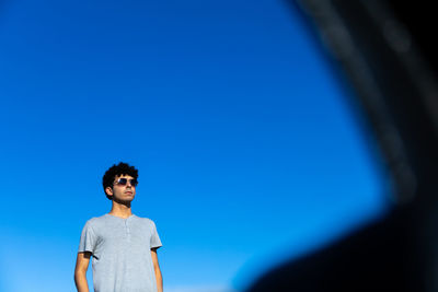 Young woman standing against blue sky