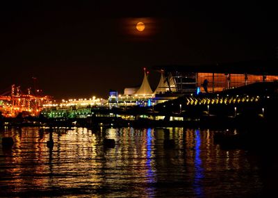 Illuminated bridge over river in city at night