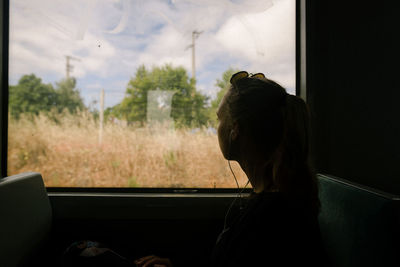 Rear view of woman looking through train window