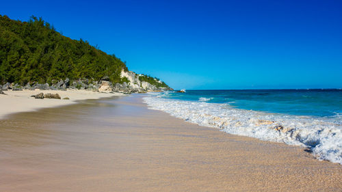 Scenic view of beach against clear blue sky