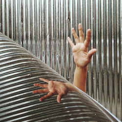 Cropped hand trapped amidst corrugated iron