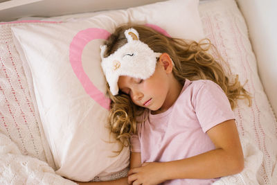 Cute girl with a sleep mask sleeps sweetly on a pillow