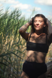 Portrait of young woman standing against trees