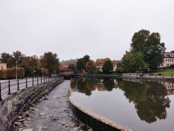 Canal amidst trees and buildings against clear sky