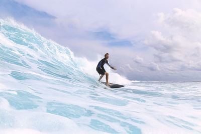 Surfer surfing on sea in front of cloudy sky