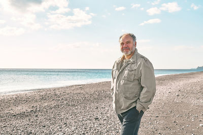 Happy middle-aged bearded man walking along deserted winter beach.