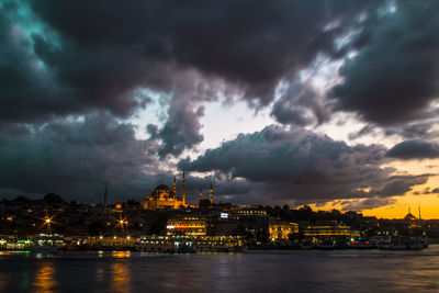 Illuminated buildings against cloudy sky at dusk