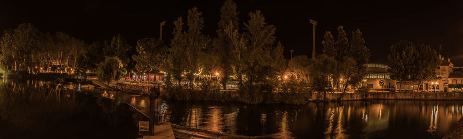 Illuminated buildings by river at night