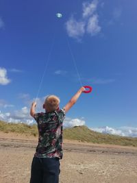 Rear view of boy flying kites against sky