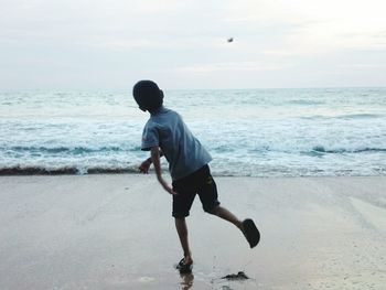 Full length of boy standing on beach against sky