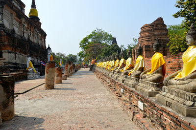 Buddha statues at temple against clear sky