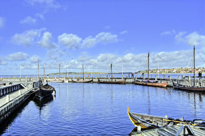 Boats moored at harbor against sky