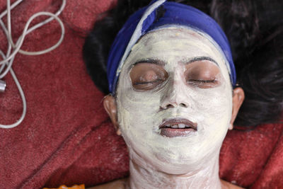 Woman wearing facial mask while lying on bed at home
