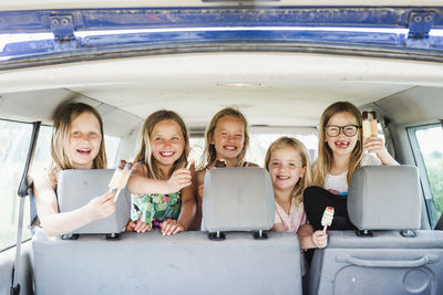 Happy girls in car holding ice lollies