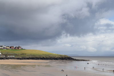 View of calm beach against cloudy sky