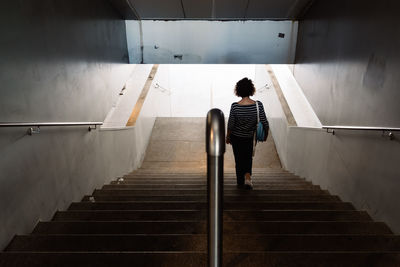 Rear view of man walking on staircase