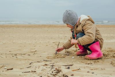 Rear view of woman standing at sandy beach