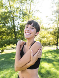 Happy young athlete hugging self in park