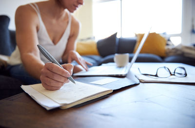 Midsection of woman using mobile phone while sitting on table