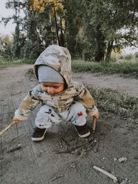 Cute boy sitting on land by tree