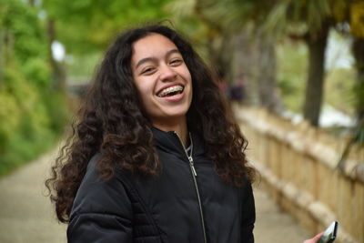 Portrait of laughing teenage girl standing in park