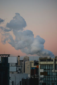 Smoke emitting from factory against sky