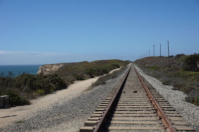 Railroad track against blue sky on sunny day
