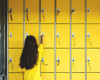 Rear view of girl using locker