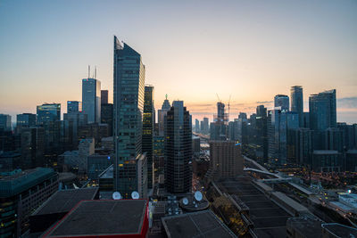 Modern buildings in city against sky during sunset