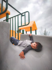 Boy lying on slide at playground