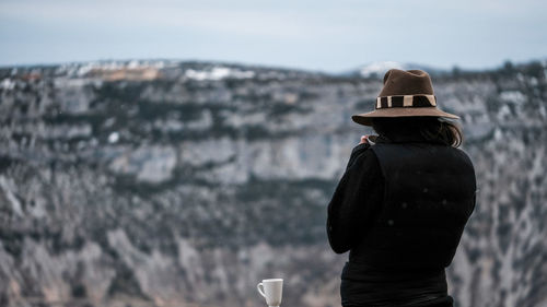 Rear view of woman standing against snowcapped mountain