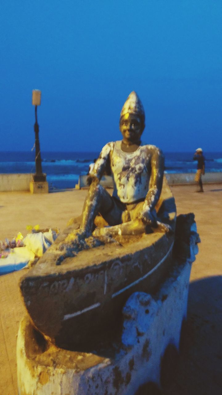 CLOSE-UP OF STATUE ON BEACH AGAINST CLEAR SKY