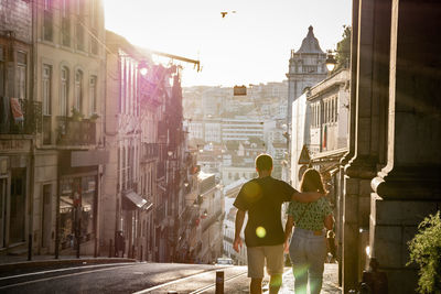 Rear view of men walking on street amidst buildings in city