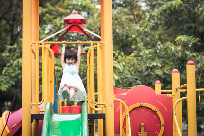 Cute girl hanging over slide in playground